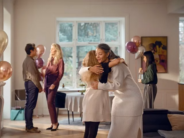 人々が抱き合ったり、会話したり、お祝いをしている様子を描いた室内写真