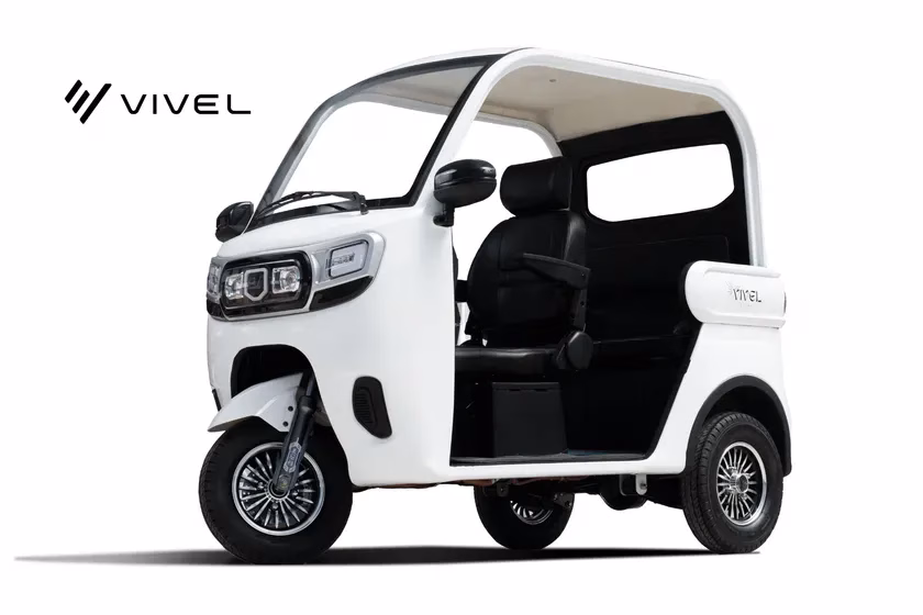 白い三輪電気自動車の画像です。VIVELというロゴが左上に表示されています。運転席と助手席があり、ドアが開いています。