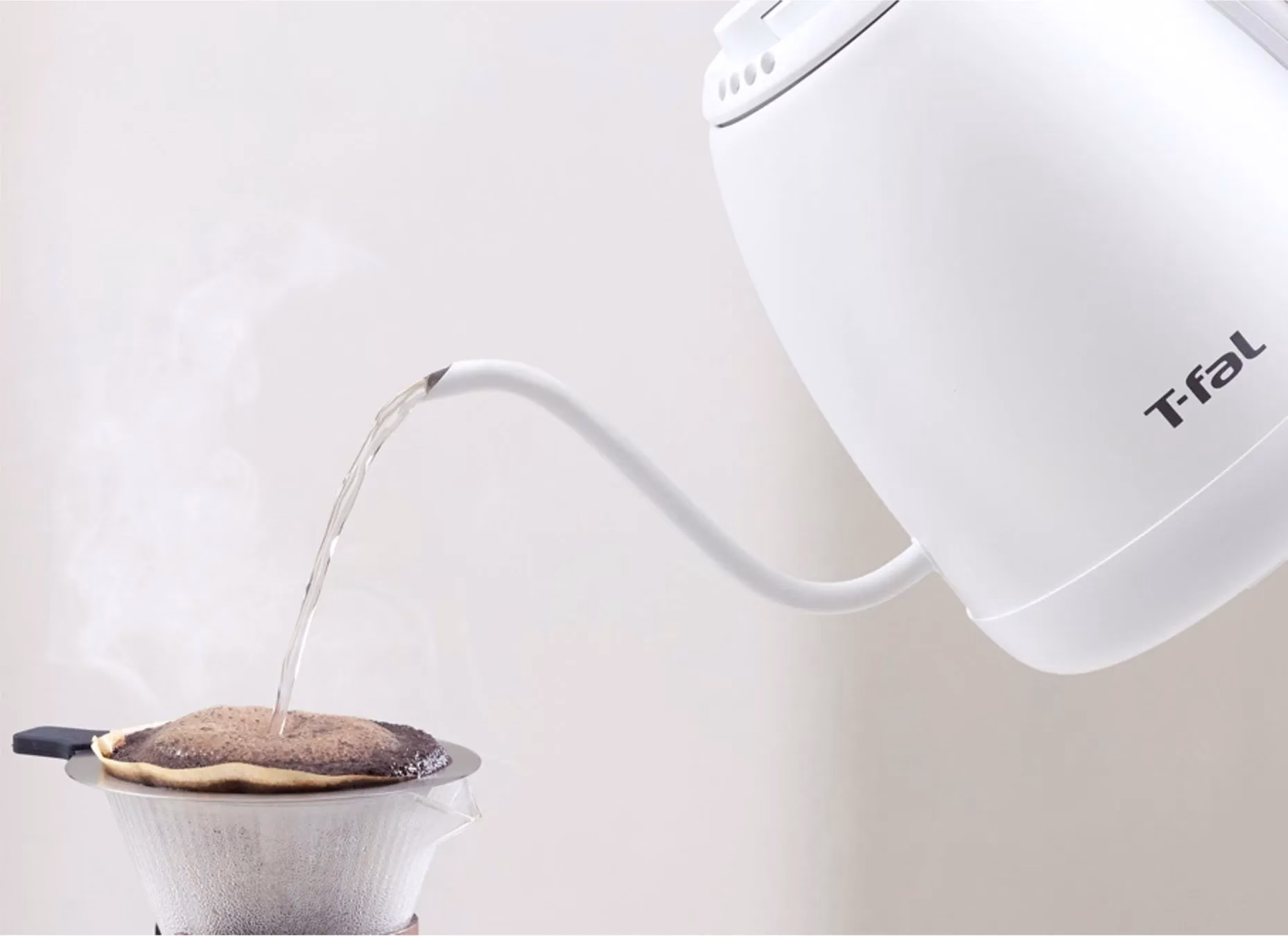 お湯を注いでコーヒーをドリップしている様子を写した写真。白い電気ケトルから細くお湯が注がれ、コーヒーフィルターにセットされたコーヒー粉に落ちている。湯気も立っている。