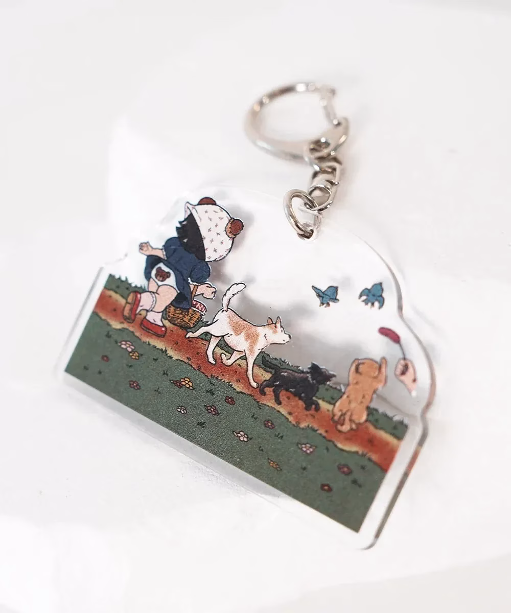 犬と子供のイラストが描かれたキーホルダー。子供が犬と一緒に歩いている様子が描かれています。