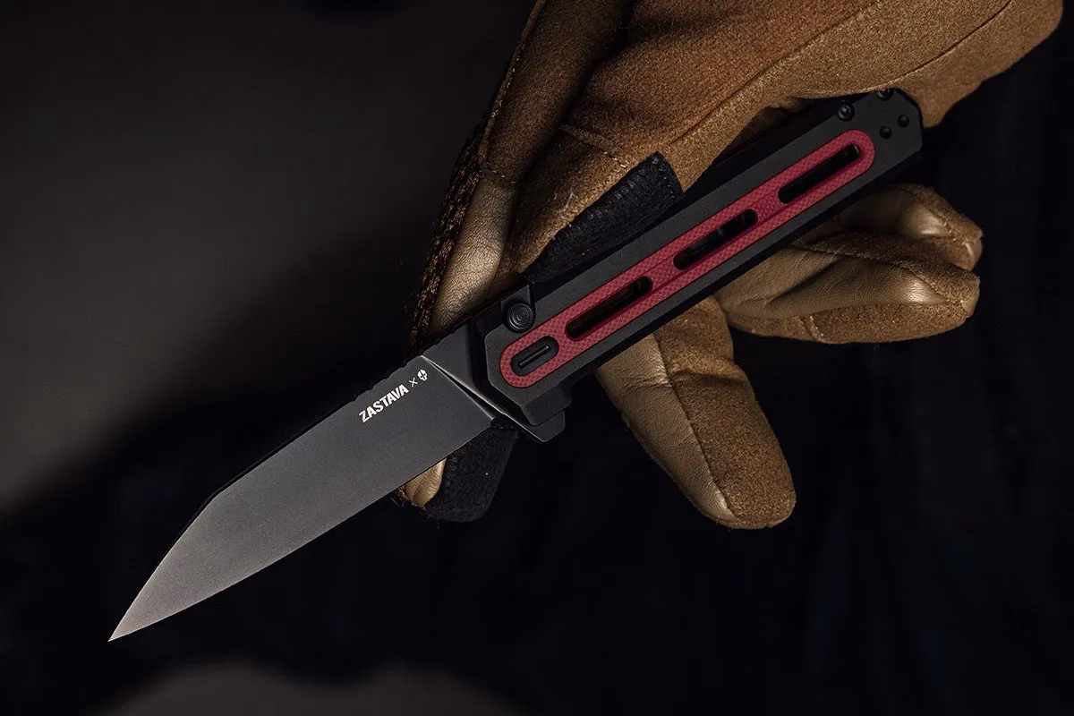 手袋をはめた手が、黒い刃と赤いアクセントのあるナイフを持っています。刃に「ZASTAVA x」