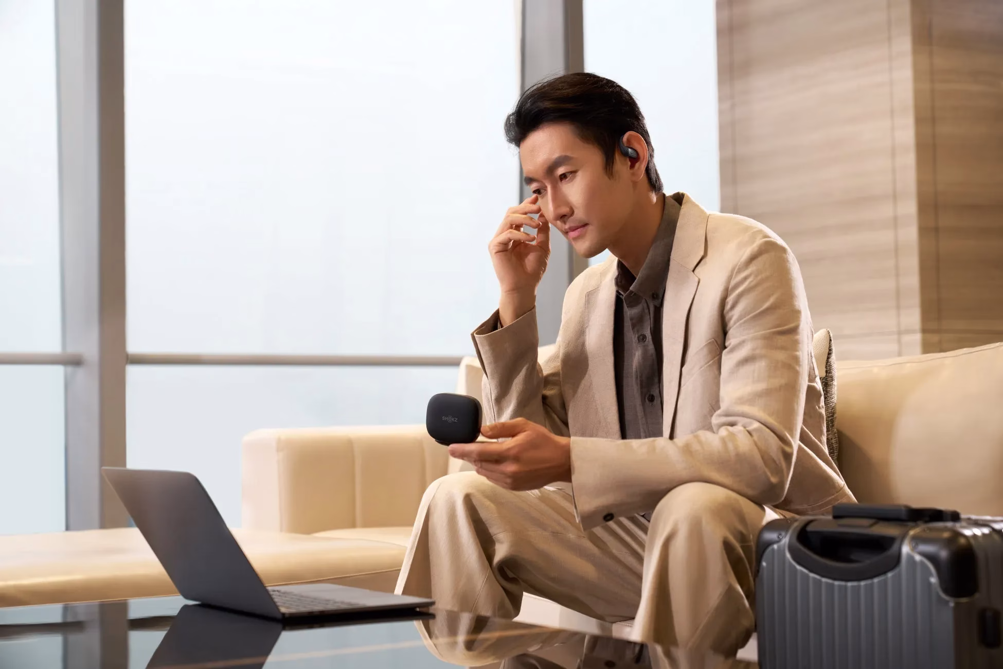 男性がイヤホンとノートパソコンを使って仕事をしている様子。