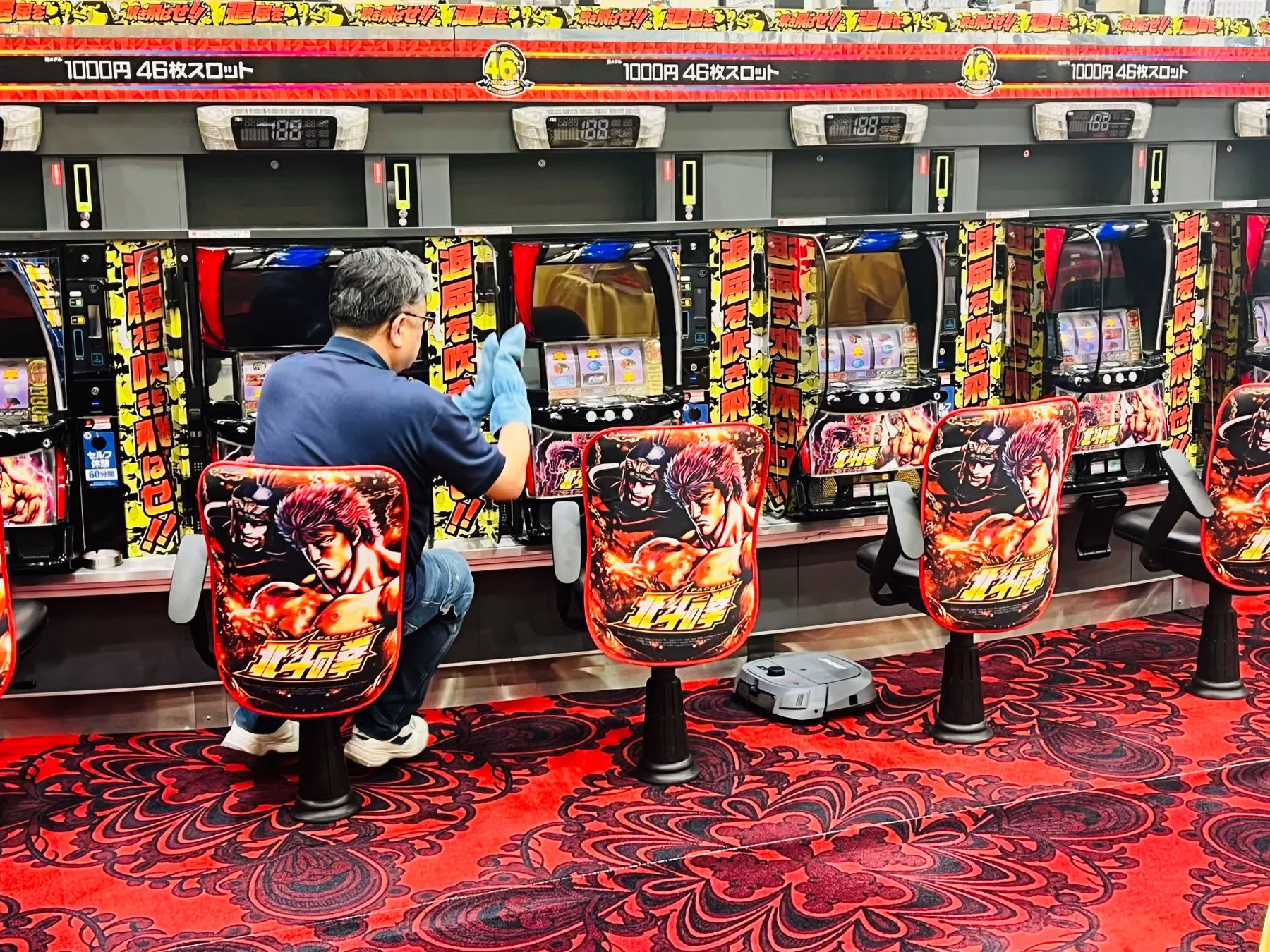 パチンコ店で、清掃員がパチンコ台の清掃をしている様子。
