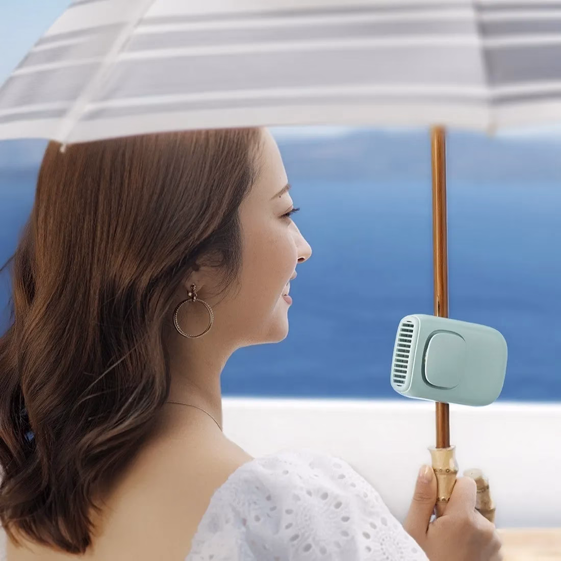 女性が日傘と扇風機を持っている