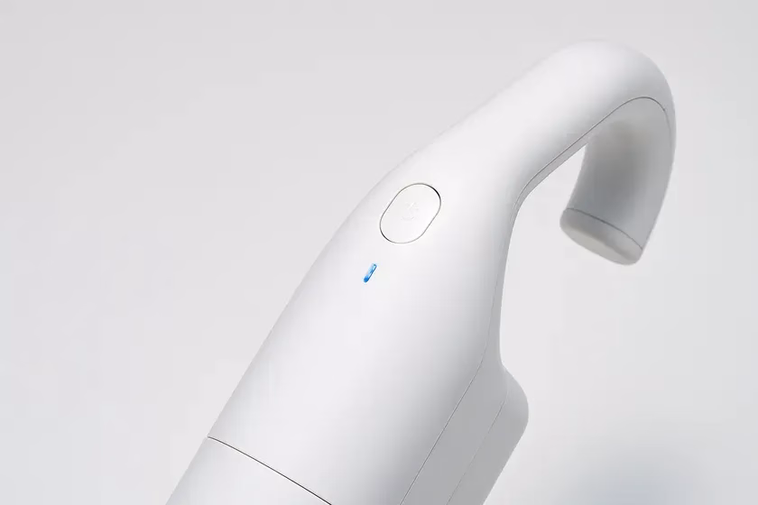 白い掃除機のクローズアップ画像。電源ボタンと青いインジケーターライトが確認できる。