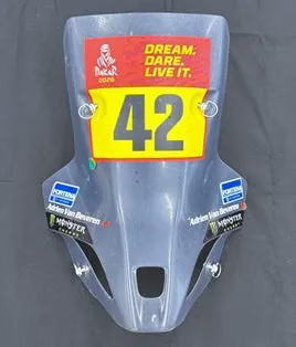 透明なバイクのフロントガラス。上部に「DREAM. DARE. LIVE IT. Dakar 2020」と書かれた赤い長方形のステッカー、その下に「42」と大きく書かれた黄色いステッカーが貼られている。フロントガラスには「Adrien Van Beveren」と書かれたステッカーや「MONSTER」のロゴも見える。